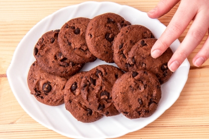 hand reaching over white plate full of chocolate cookies